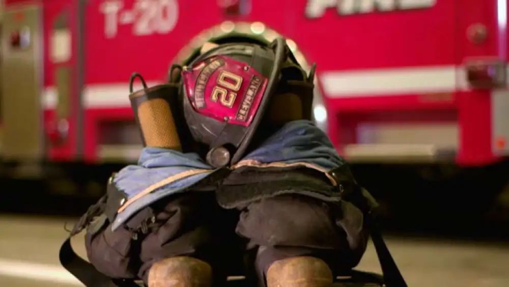 image of firefighter's helmet, pants and boots in front of fire emergency vehicle