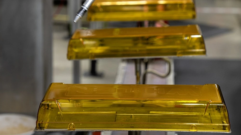 image of amber lenses moving to the spray-off area of assembly line in Whelen Engineering manufacturing facility