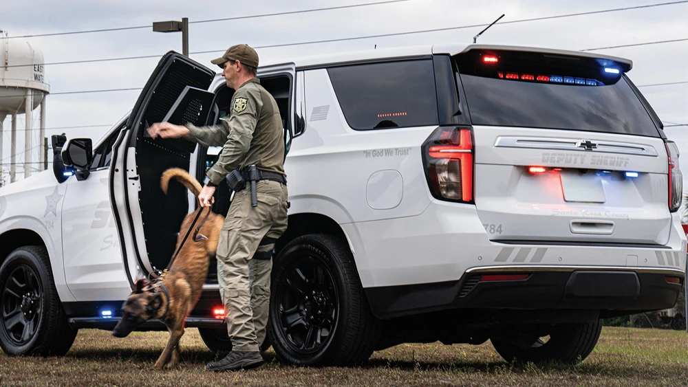 image of K-9 unit dog exiting rear of police emergency vehicle with handler