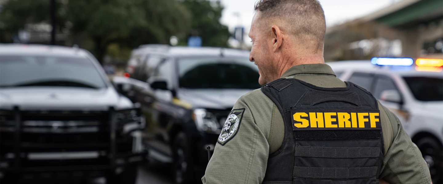 image of police sheriff standing in front of row of police emergency vehicles