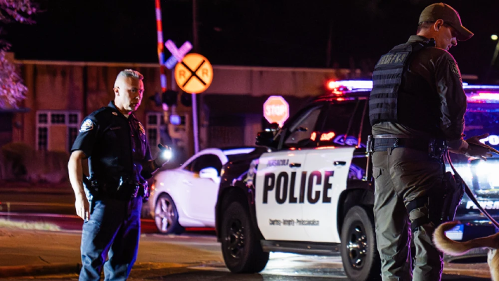 image of two police officers and police vehicle with flashing lights at scene of nighttime incident