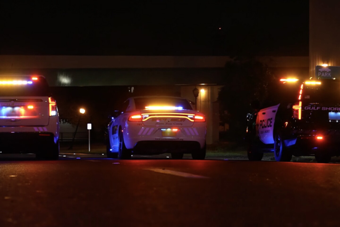 image of three police emergency vehicles with flashing lights at nighttime