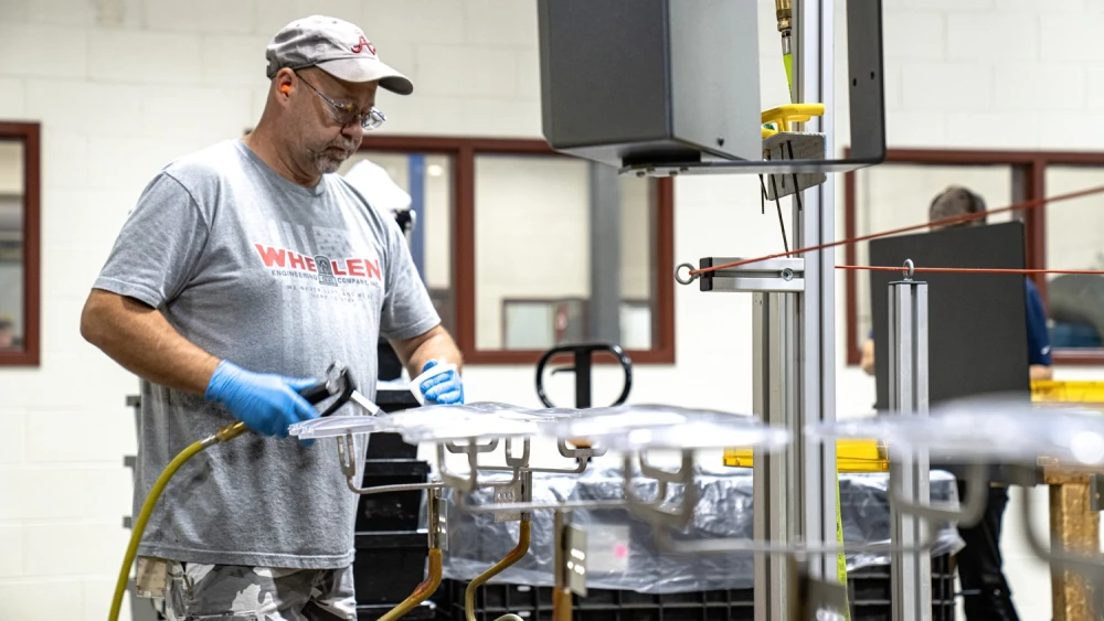 image of Whelen factory employee cleaning lighting parts with isopropyl alcohol before drying them with compressed air